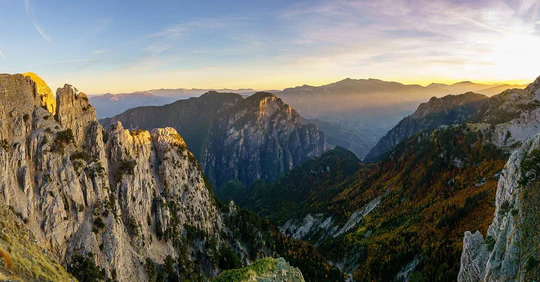 Limestone cliffs above a forested valley in evening light